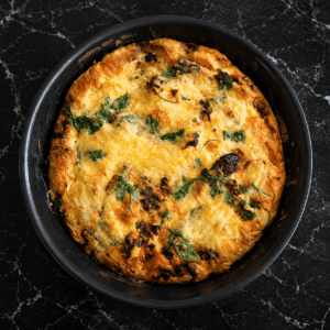 A soft-set frittata with onion, sun‑dried tomatoes, and parmesan, finished under the grill until lightly browned.